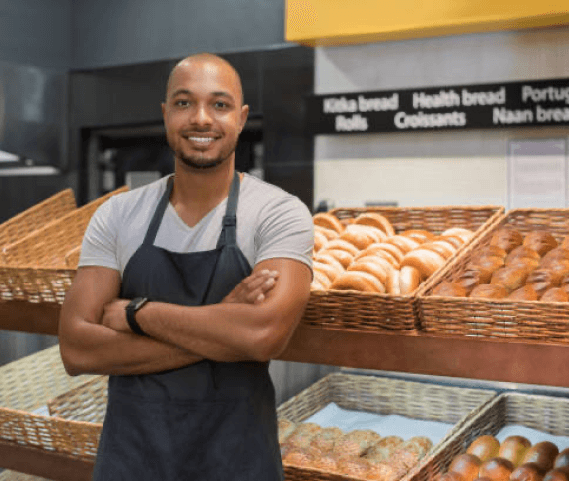 Homem sorrindo com pães ao fundo